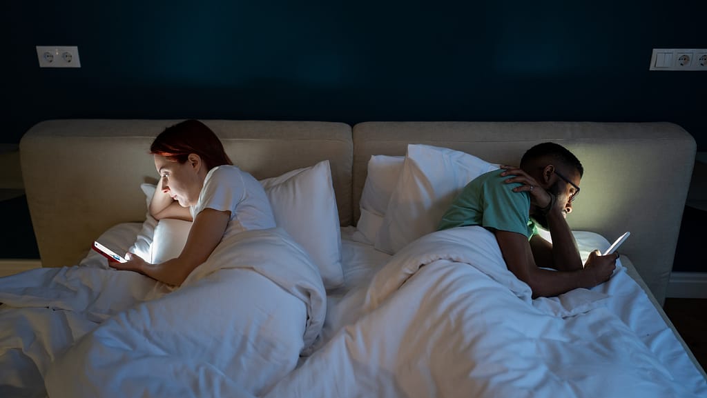 A couple lying in bed back-to-back in bed